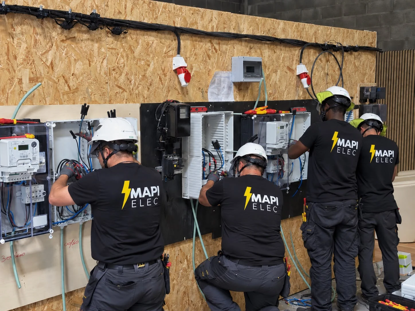 Quatre techniciens MAPI Elec au travail sur un banc de formation au comptage